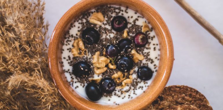 Top view of a nutritious bowl with yoghurt, blueberries, chia seeds, and walnuts.