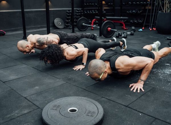 Fitness enthusiasts performing push-ups in a Mexico City gym. Emphasizing teamwork and strength.